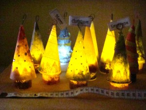 Eleven Lutradur Christmas trees illuminated by battery operated tea lights.
