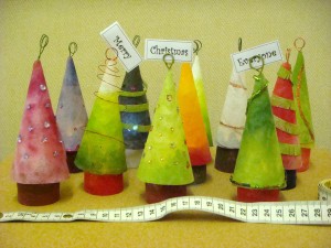 Eleven little Christmas trees decorated in shades of green and red and decorated with tiny coloured beads and wire.