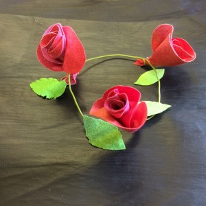 A trio of red rose buds and green leaves made from Evolon Soft attached to a ring of green garden wire.