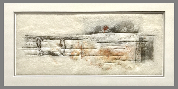 A framed mixed media picture of an abstract pale landscape, with a few grey trees in the distance and a single small brown tree set in the midst of the group. Horizontal and vertical lines are scattered throughout the picture, possibly to represent walls , ditches or fencing.