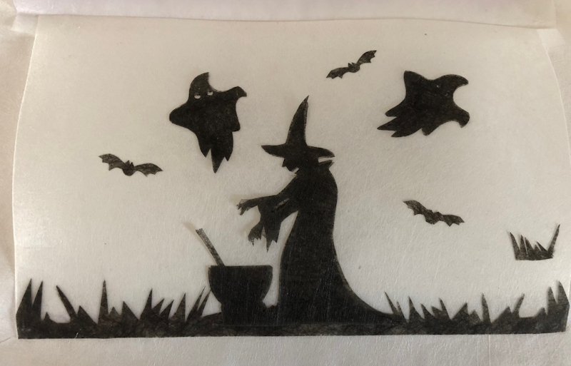 A witch next to a cauldron is in the centre of the picture, two ghosts and three small bats are seen flying around her. All are black images against a white background.