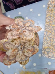 Beige and gold coloured flowers attached to a polystyrene bauble.