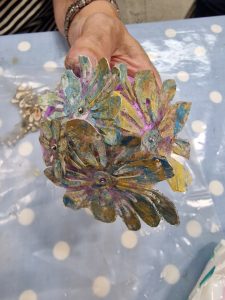 Blue, green and purple coloured Lutradur flowers attached to a painted polystyrene bauble.