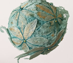 A decorative bauble which has been covered with simple daisy type flowers cut from Lutradur and painted pale green, highlighted with metallic paint and gold bead centres. 