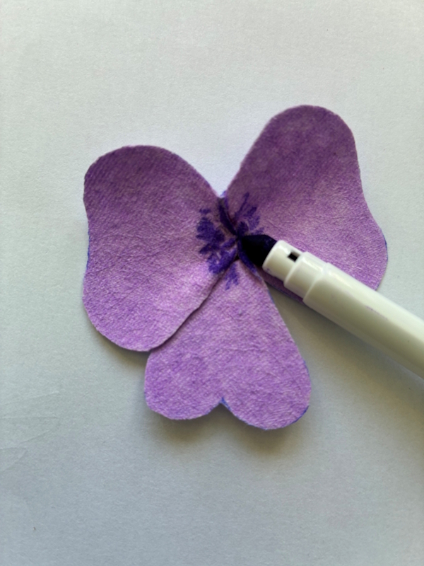 A darker coloured fibre pen is used to colour in the very centre of the petals. The ink will naturally run into the main colour, but can encouraged to spread further by lightly spraying it with water.