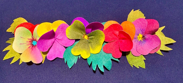 A row of five pansies and three set of leaves against a dark blue background. All the pansies have different colour combinations.